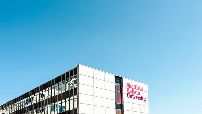 Owen Building at Sheffield Hallam. At the bottom of the picture is the top of a large white building, with the Hallam logo on the side. Above and around it is clear blue sky.